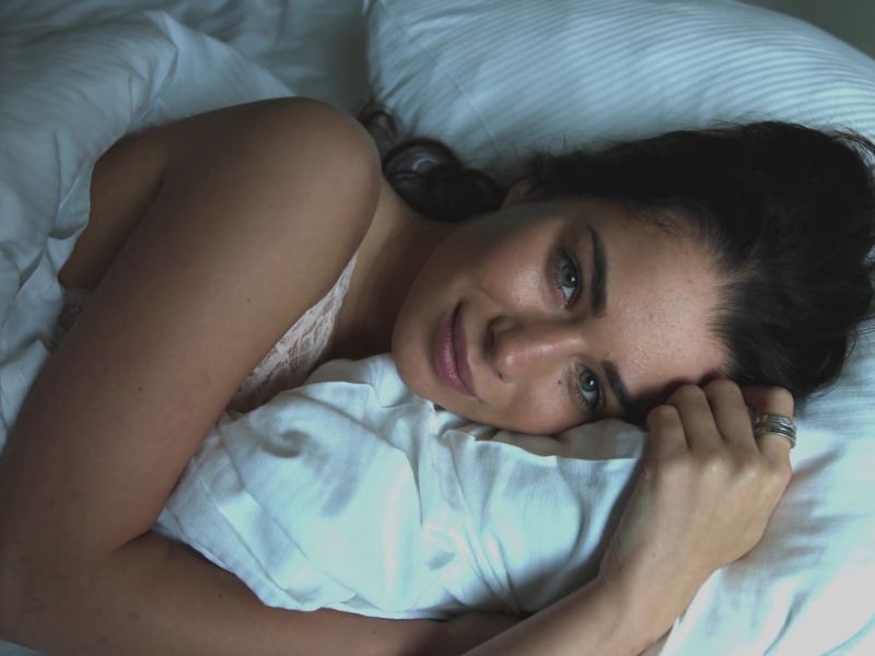 devojka leži u krevetu sa zagrljenim jastukom